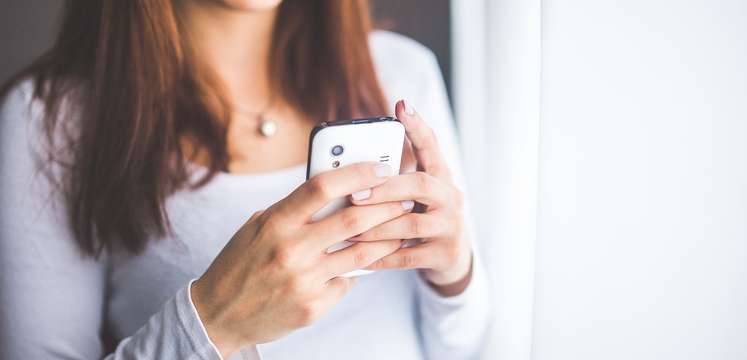Eine junge Frau hält ein Handy in der Hand und tippt etwas ein Eine junge Frau hält ein Handy in der Hand und tippt etwas ein