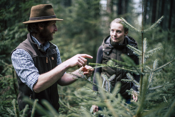 Waldbesitzer erklärt Frau die Vielfalt in seinem Wald