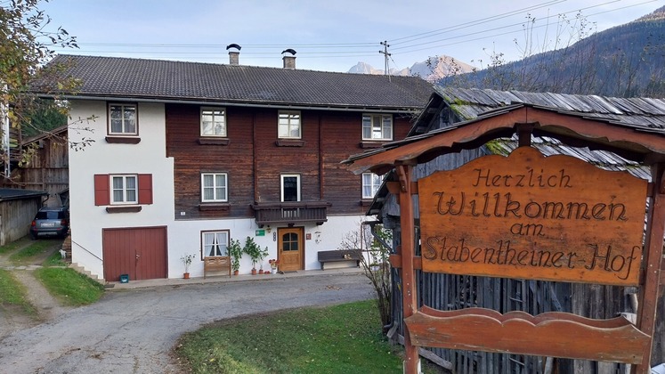 Man sieht das Hofgebäude und das Hofschild mit dem Namen darauf.