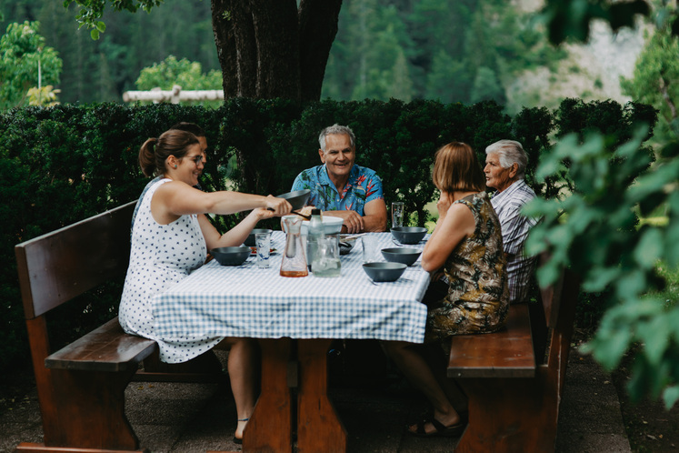 Vier Personen sitzen an einem Tisch mit Essen und Trinken