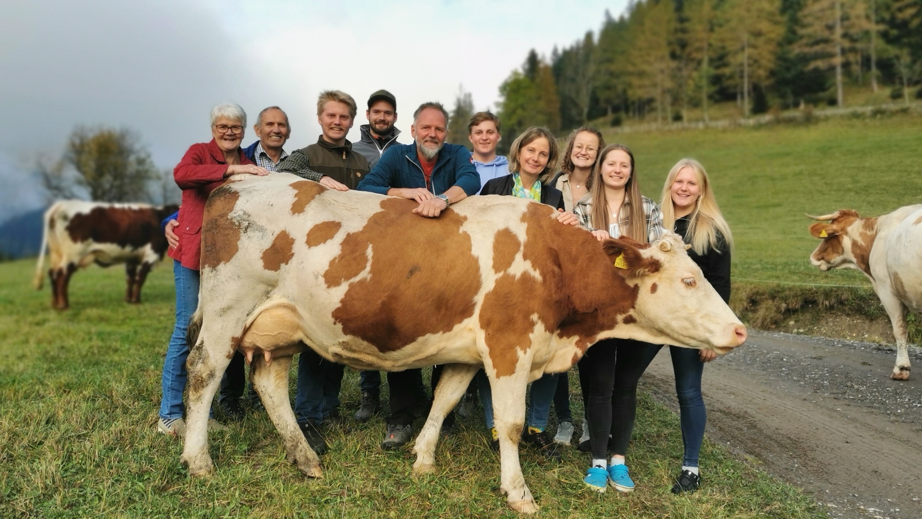 Eine große Familie steht hinter einer Kuh