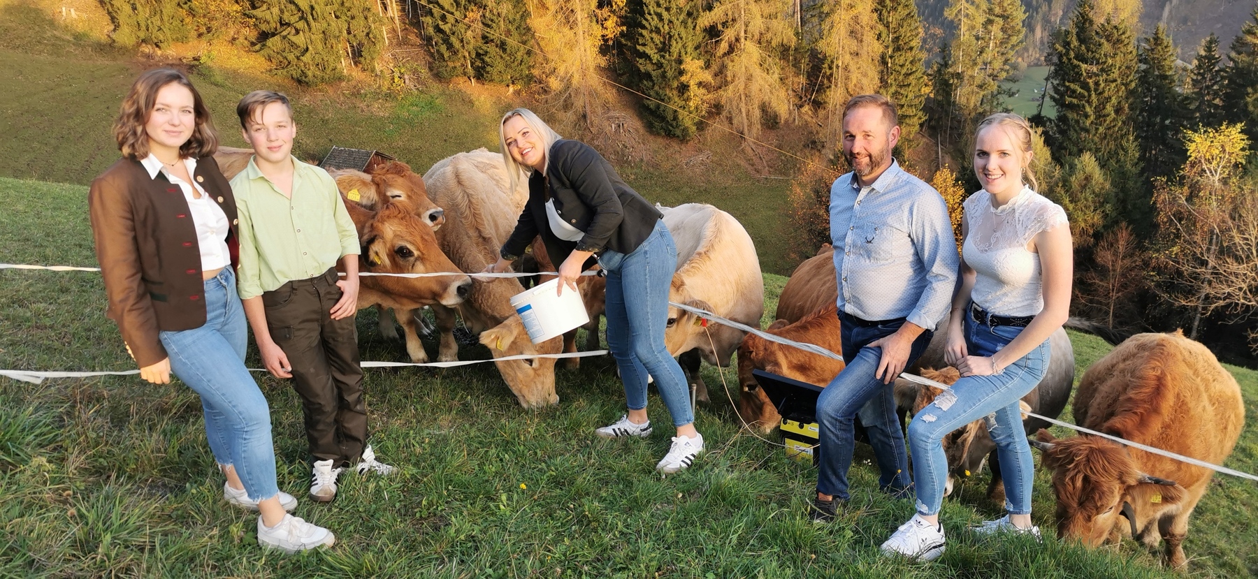Eine Familie steht vor einer Gruppe Rinder