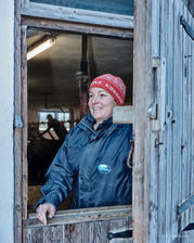 Eine Frau lächelt aus dem Stallfenster raus