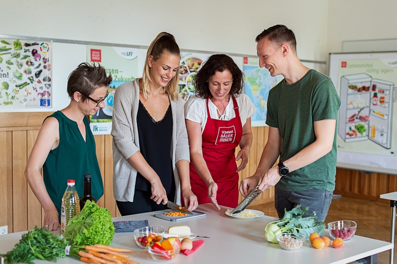 3 Frauen und 1 Mann stehen rund um einen Tisch und schneiden Gemüse.