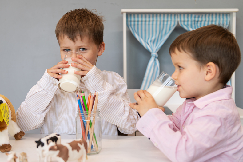 Zwei Buben trinken ein Glas Milch. 