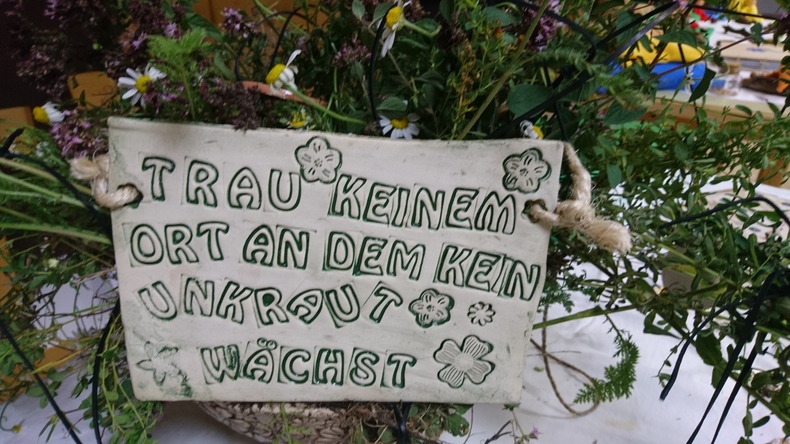 Auf einer Tontafel steht "Trau keinem Ort, an dem kein Unkraut wächst".