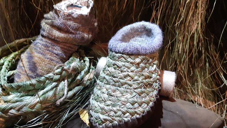 Ein Raschpatschen - Schuh aus Gras, ein selbstgestrickter Wollsocken in einem Raschkorb 