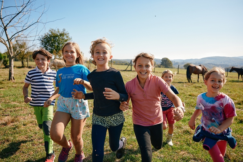 Herumlaufende, spielende Kinder auf einer Wiese.