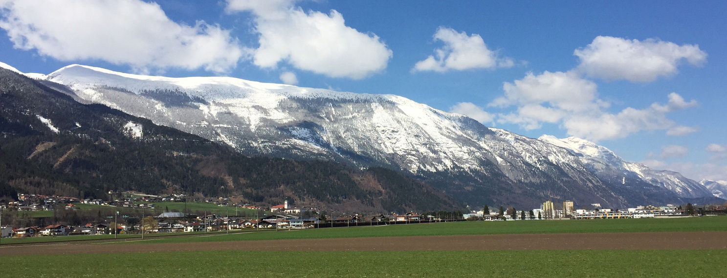 Landschaft mit Feldern, Wald und Bergen im Bezirk Schwaz