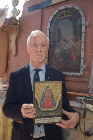 Pfarrer Rupert Reindl mit dem renovierten Bild der Emmaus-Jünger (re. hinten) und einem Marien-Votivbild © Standl