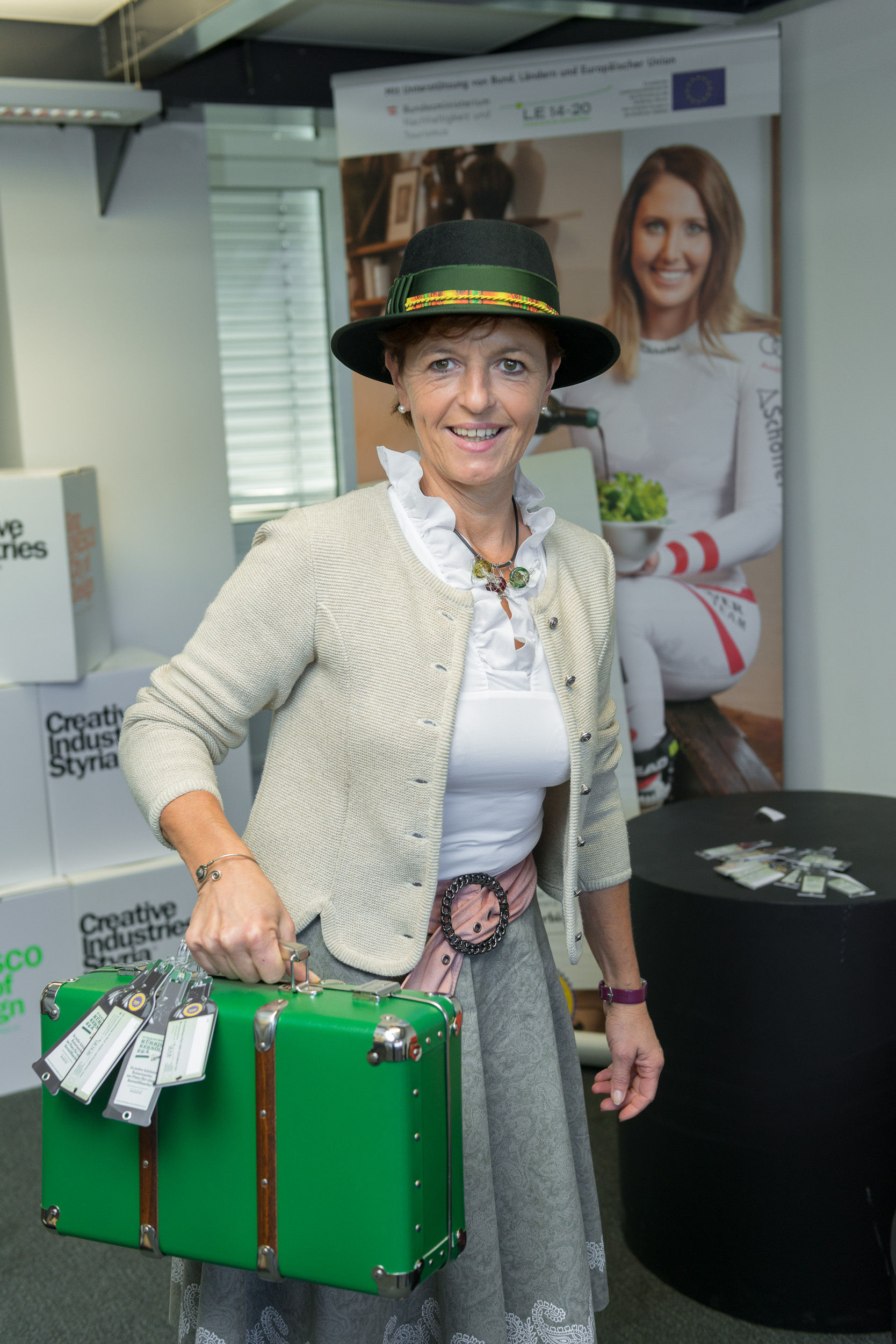 In jeder kleinen Reisetasche ist Platz für eine Kernölflasche. Vizepräsidentin Maria Pein mit den Kofferanhängern in Kernölflaschen-Form. © Kristoferitsch