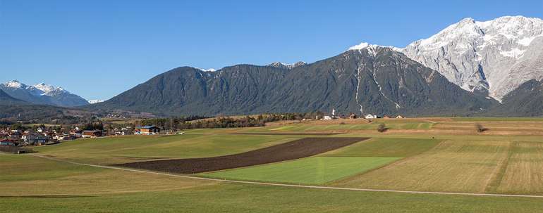 Tiroler Landschaft mit Dorf und Feldern, Wald und Bergen