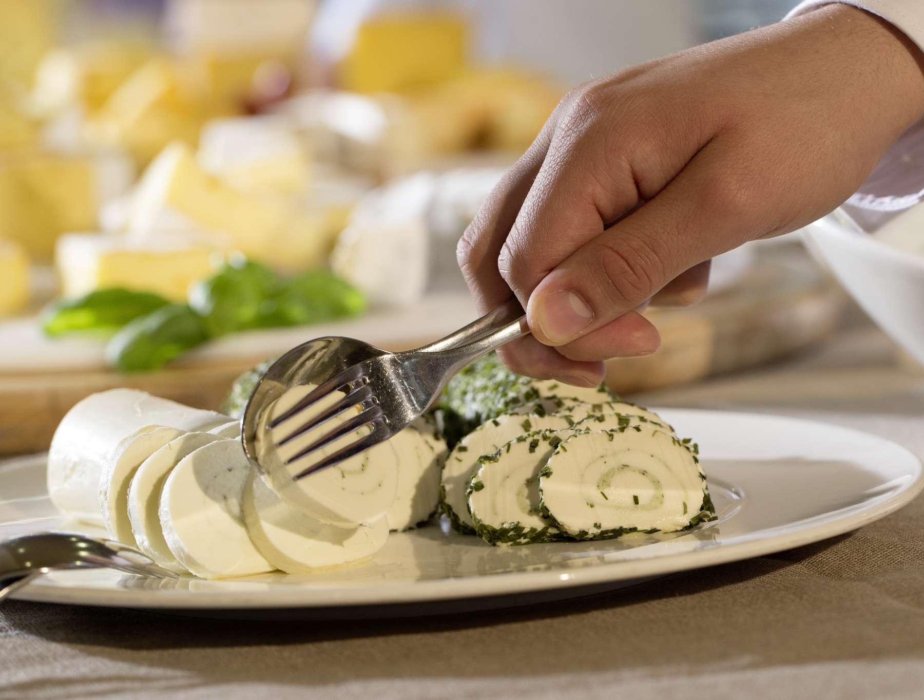 Frischkäse wird mit Besteck vom Teller gehoben. © AMA Marketing