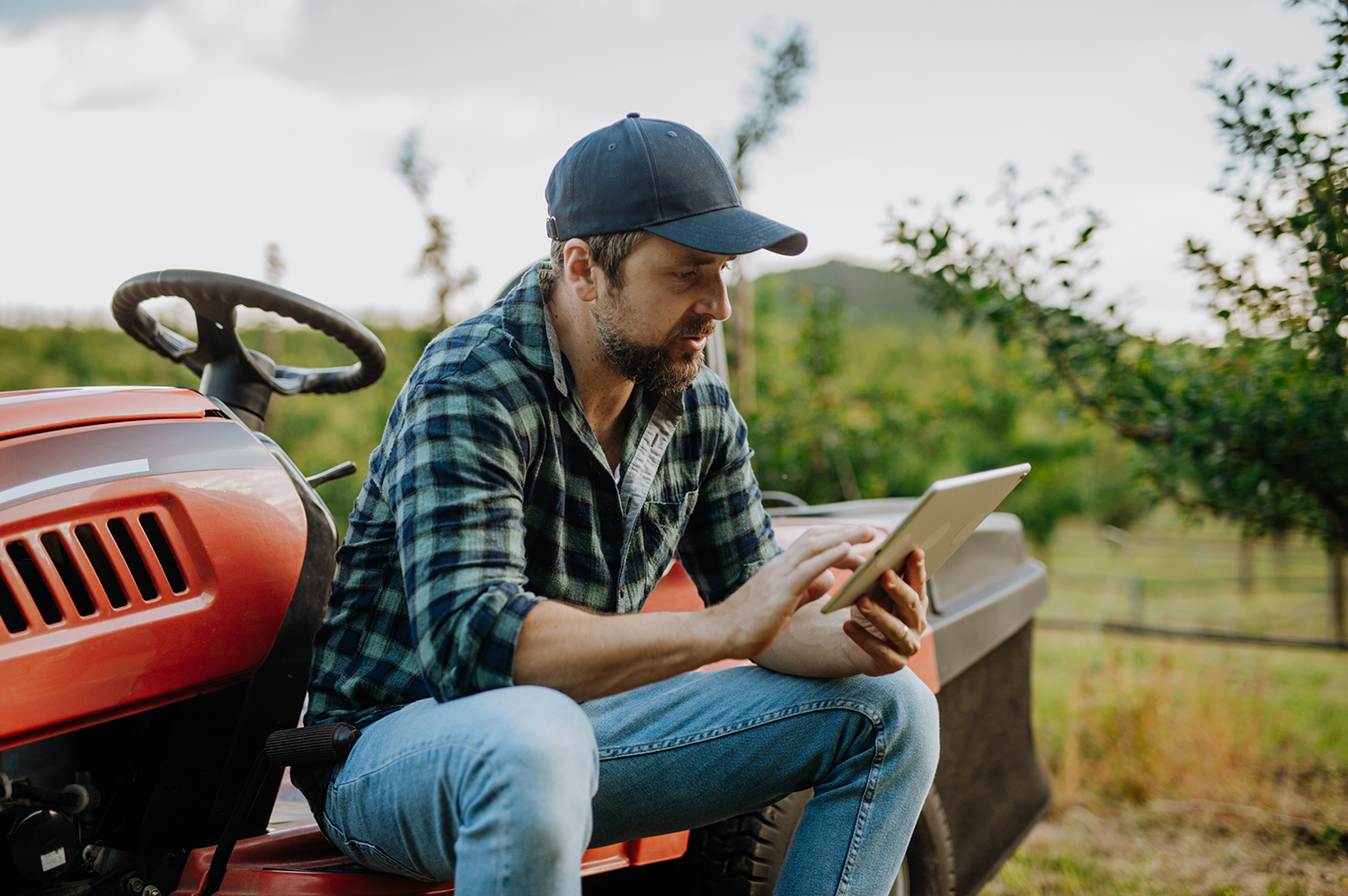 Bauer sitzt auf Traktor und liest am IPad © Halfpoint – stock.adobe.com